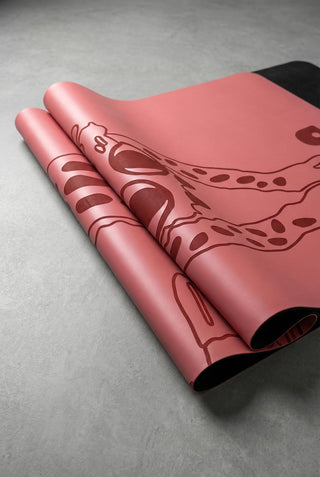 Detail of a Yoga mat folded with black natural rubber base and laser printed design on a concrete surface.