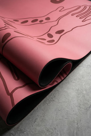 Detail of a Yoga mat folded with black natural rubber base and laser printed design on a concrete surface.