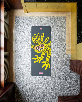 Yoga mat with a colorful design on a speckled gray floor.