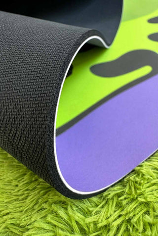 Close-up of a textured mat with green, purple, and black colors on a green surface.